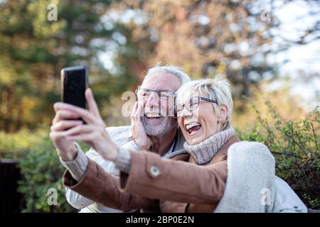Two senior couple taking selfie in park Stock Photo