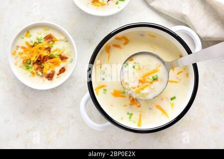 Delicious potato creamy soup with bacon and cheddar cheese in bowl on light stone background. Healthy diet dish for dinner. Top view, flat lay Stock Photo