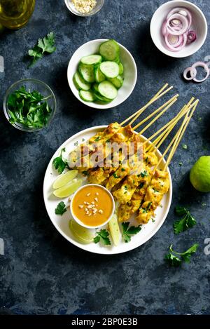 Chicken satay with peanut sauce. Grilled chicken skewers served with peanut dipping sauce. Tasty meal for dinner or party appetizers. Blue stone backg Stock Photo