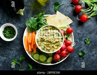 Baba ganoush (roasted eggplant dip) in bowl and fresh organic vegetables over blue stone background. Healthy eating. Vegetarian vegan food concept. To Stock Photo