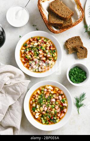 Traditional cold russian soup Okroshka with sausage, vegetables and kvass over light stone background. Top view, flat lay Stock Photo