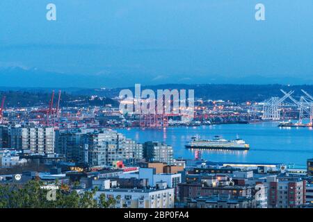 big ferry moving into downtown Seattle with industrail port background at night time,Seattle,Washington,usa. Stock Photo
