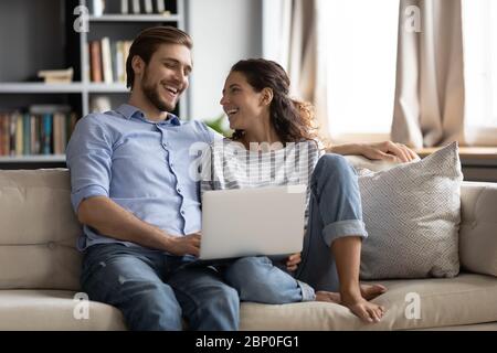 Happy couple relax on sofa using laptop together Stock Photo