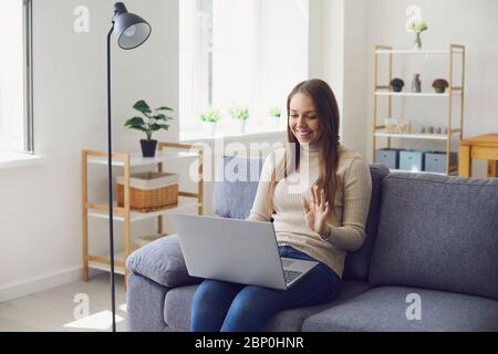Online work at home. A woman works at a table in using a laptop she speaks with a partner through the video call chat application at home. Stock Photo