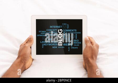 Closeup of African American guy holding tablet computer with blogging related words on screen, collage Stock Photo