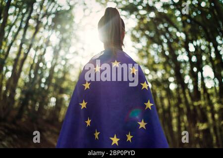 Child teenager girl at nature background an European Union flag on her shoulders Stock Photo