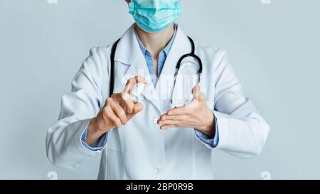 Disinfection concept. Doctor in protective mask rubs hands with antiseptic Stock Photo