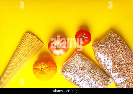 Food supplies for quarantine on yellow background. Pasta, vegetables, fruits, cereals. Stock Photo