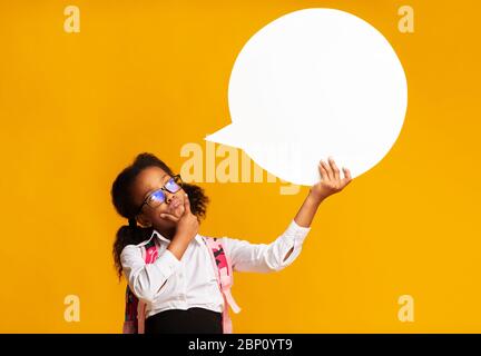 Thoughtful School Girl Holding Speech Bubble Thinking On Yellow Background Stock Photo