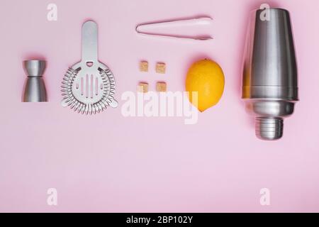 Shaker, jigger, and other bar tools with lemon and sugar on pink background Stock Photo