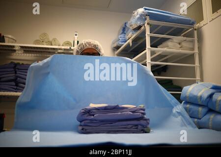 A a laundry worker prepares clean reusable gowns to distribute to medical workers across the hospital in the laundry and linen room at The Royal Blackburn Teaching Hospital in East Lancashire during the outbreak of the coronavirus disease. Stock Photo