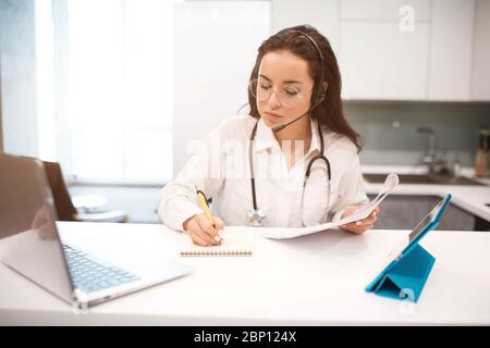 telemedicine. A woman doctor is working from home because of the Cowid-19 coronavirus pandemic. She consults patients online. Stock Photo