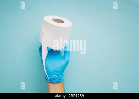 Hand holding roll of toilet paper over blue background Stock Photo
