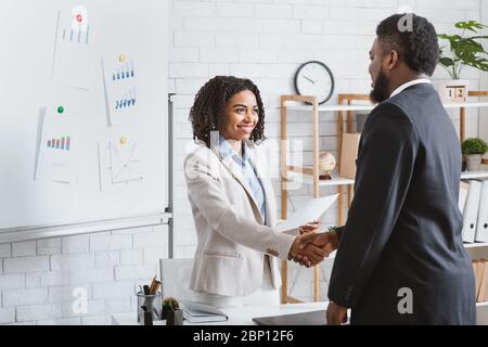 Smiling HR manager shaking hands with young applicant at job interview in office. Blank space Stock Photo