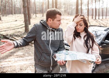 Man and woman lost in the forest. They are standing with a map and do not know where to go next Stock Photo