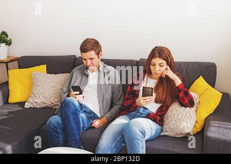 Young couple, man and woman using their mobile phones