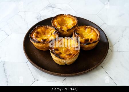 Pasteis de Nata or Belem Tart. Portuguese Custard made with Egg, Cinnamon, Sugar and Flour on Wooden Plate. Traditional Dessert. Stock Photo