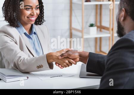 African American hiring manager shaking hand of vacancy candidate during employment interview in office Stock Photo