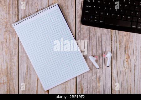 Workplace with laptop computer keyboard a desk with paper notebook for notes written small wireless headphones Stock Photo