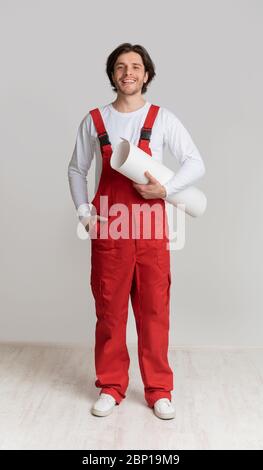 Smiling construction worker holding project plan in hands and posing to camera Stock Photo