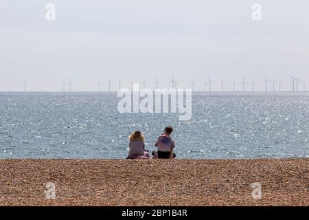couple sitting on beach with wind farm Stock Photo