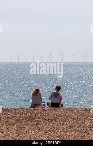 couple sitting on beach with wind farm Stock Photo