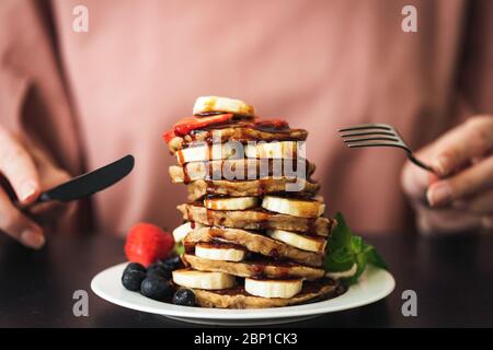 Pancakes with banana chocolate sauce and strawberries. Stack of delicious pancakes. Sugar bomb, carbohydrates food, sweet breakfast pancakes Stock Photo