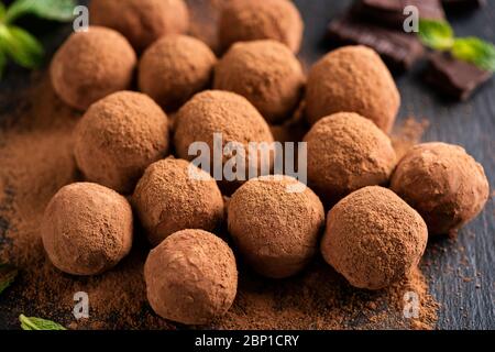 Homemade dark chocolate truffles on black slate, closeup view. Cocoa chocolate truffles Stock Photo