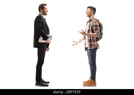 Full length profile shot of a man in a black suit holding books and talking with a male student isolated on white background Stock Photo