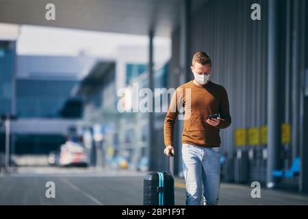 Man wearing face mask and walking to airport terminal. Themes traveling during pandemic and personal protection. Stock Photo