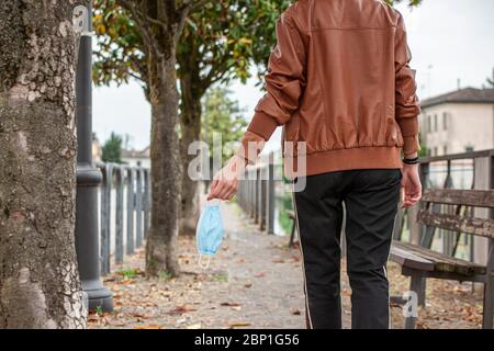 Detail of a girl's hand holding a medical mask while walking on the street 2 Stock Photo