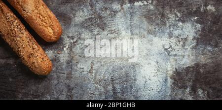 Fresh bakery food. Crusty loaves of mixed breads and buns and ears of wheat on rustic table background. Top view and copy space for text. Banner wide Stock Photo