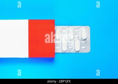 blister pack with pills in a red-white box on a blue background. copy space. flat lay Stock Photo