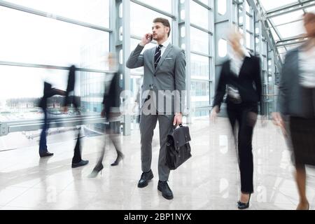 Business man talking on phone standing in a crowd of walking people Stock Photo