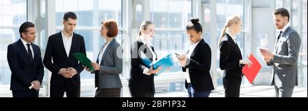 Corporate business team, people standing by the window at break and talking discussing documents Stock Photo