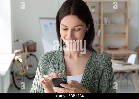 Close up smiling attractive young businesswoman using smartphone. Stock Photo