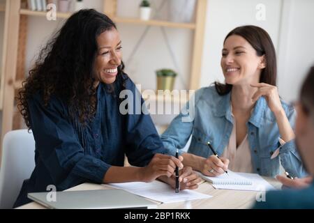 Smiling african american businesswoman telling employees about project in coworking. Stock Photo