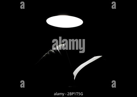 Open book on a table lamp in the dark Stock Photo