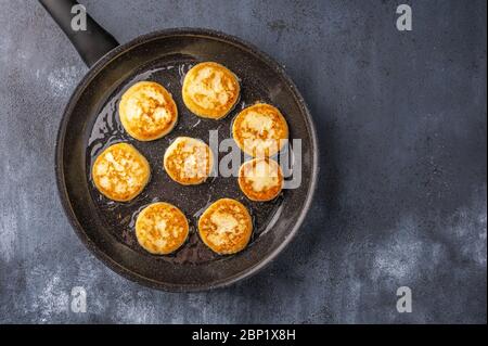 Homemade toasted cheesecakes in a frying pan on a dark wooden background. Top view. Copy space Stock Photo