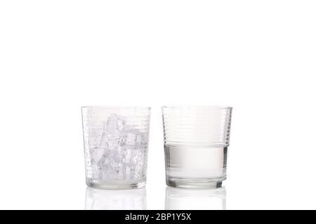 Ice melting concept with one tumbler glass with condensation droplets on the outside and full of ice and a second image of another tumbler glass half Stock Photo