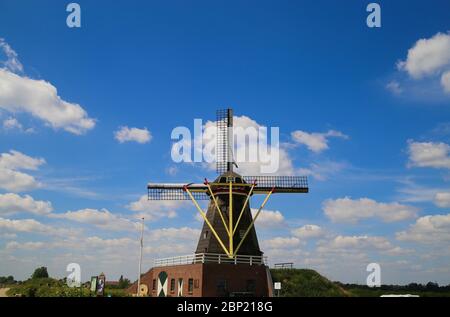 Beesel, Netherlands - May 17. 2020: View on isolated typical dutch windmill (Molen de grauwe beer) in rural landscape against blue sky with cumulus cl Stock Photo