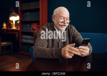 Elderly man using mobile phone in home office Stock Photo