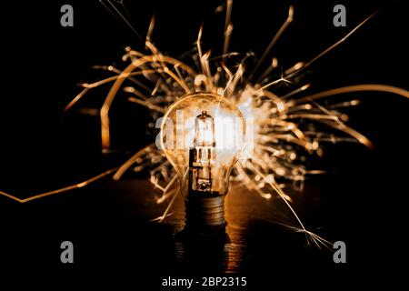 Electricity. Lightbulb lit up with sparklers behind it. Bright idea, bright spark Stock Photo