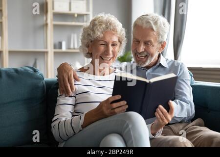 Retired people enjoying reading favorite novel literature bestseller at home. Stock Photo
