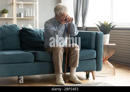 Exhausted disabled middle aged old man leaning on walking cane. Stock Photo