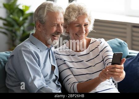 Hoary elderly woman taking selfie shot with happy old husband. Stock Photo