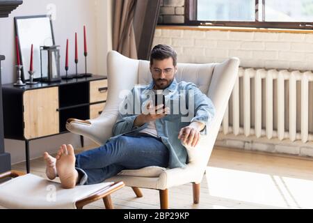 Millennial man relax in chair using cellphone device Stock Photo