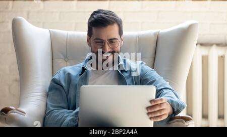 Happy young man relax in chair using laptop Stock Photo