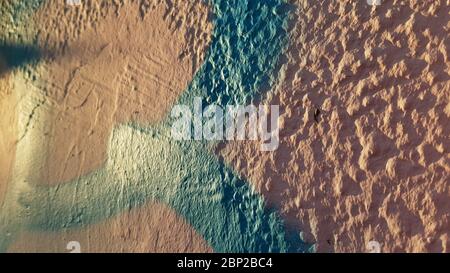 Pink painted textured wall surface closeup with blue paint stripe in bright sunlight. Plaster wall structure of old building. Abstract background Stock Photo