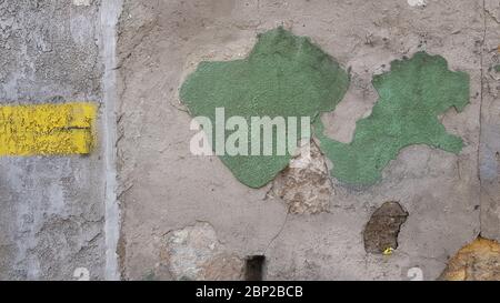 Ruined cement wall with green paint stains in shape of world map. Abstract background of construction repairs with copy space Stock Photo